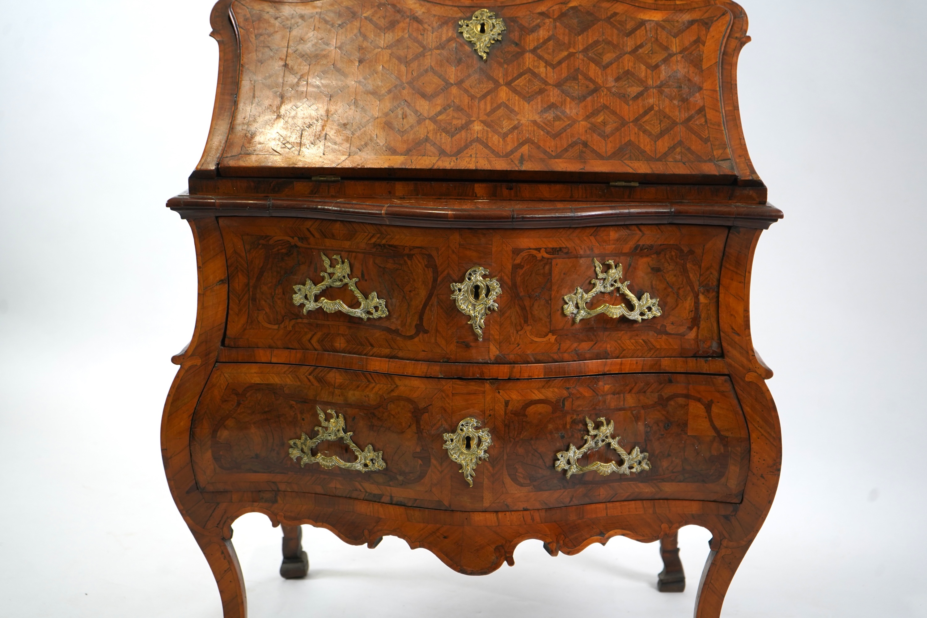 A mid 18th century North Italian or Maltese walnut and olive wood gilt metal mounted serpentine bureau cabinet